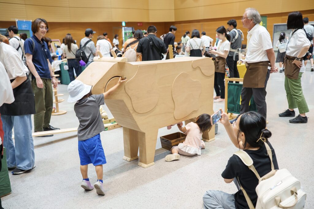 仙台アエルの木のおもちゃひろばで、木の玉ボールプールや様々な木製玩具で遊ぶ大勢の親子連れの様子