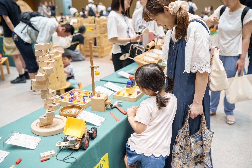 仙台アエルの木のおもちゃひろばで、木の玉ボールプールや様々な木製玩具で遊ぶ大勢の親子連れの様子