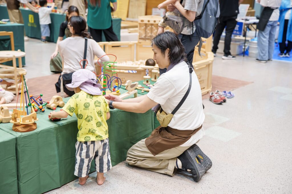 仙台アエルの木のおもちゃひろばで、木の玉ボールプールや様々な木製玩具で遊ぶ大勢の親子連れの様子