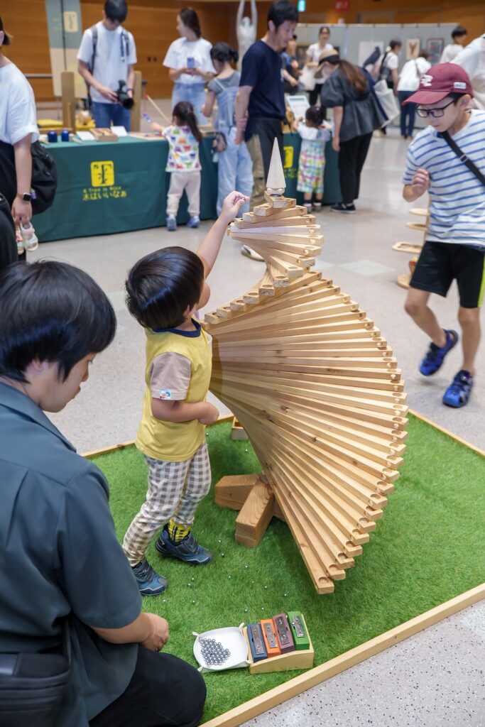 仙台アエルの木のおもちゃひろばで、木の玉ボールプールや様々な木製玩具で遊ぶ大勢の親子連れの様子