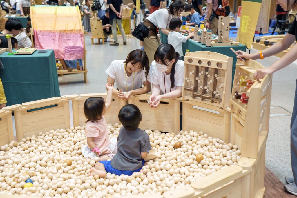 仙台アエルの木のおもちゃひろばで、木の玉ボールプールや様々な木製玩具で遊ぶ大勢の親子連れの様子