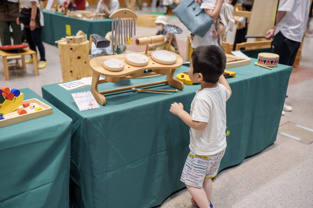 仙台アエルの木のおもちゃひろばで、木の玉ボールプールや様々な木製玩具で遊ぶ大勢の親子連れの様子