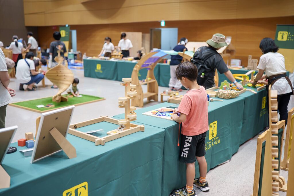 仙台アエルの木のおもちゃひろばで、木の玉ボールプールや様々な木製玩具で遊ぶ大勢の親子連れの様子