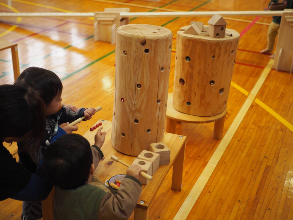 秋保市民センターの大ホールで開催された「おもちゃのひろば」で、木のボールプールや工作を楽しむ親子連れの様子
