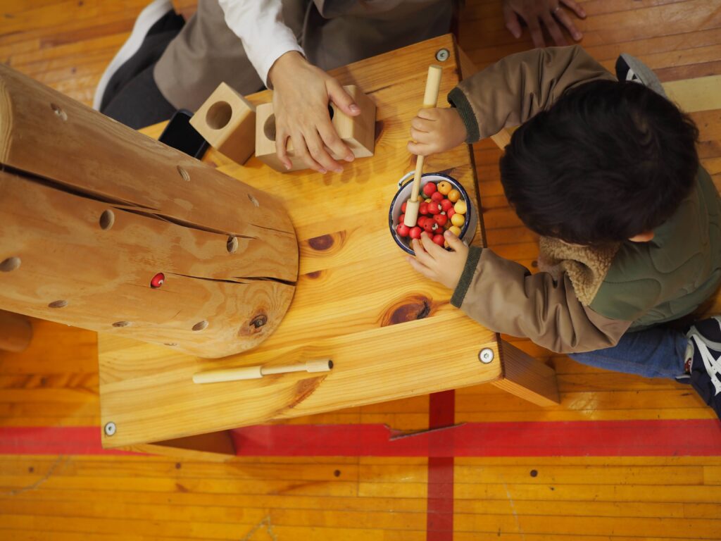 秋保市民センターの大ホールで開催された「おもちゃのひろば」で、木のボールプールや工作を楽しむ親子連れの様子