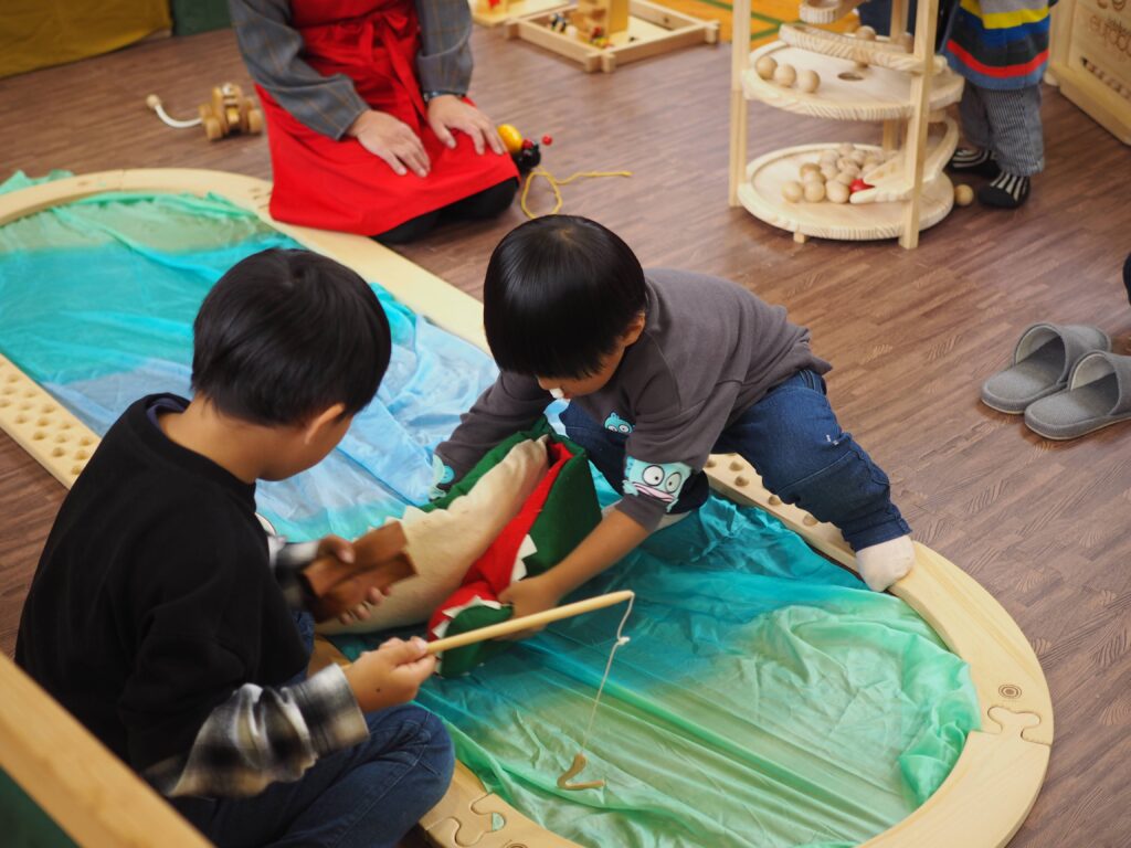 秋保市民センターの大ホールで開催された「おもちゃのひろば」で、木のボールプールや工作を楽しむ親子連れの様子