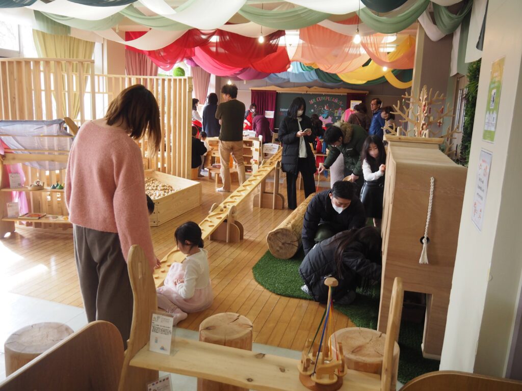 木育広場里山エスクエラの1周年イベントで、おもちゃコンサルタントと子どもたちが積み木やワークショップで遊んでいる賑やかな風景