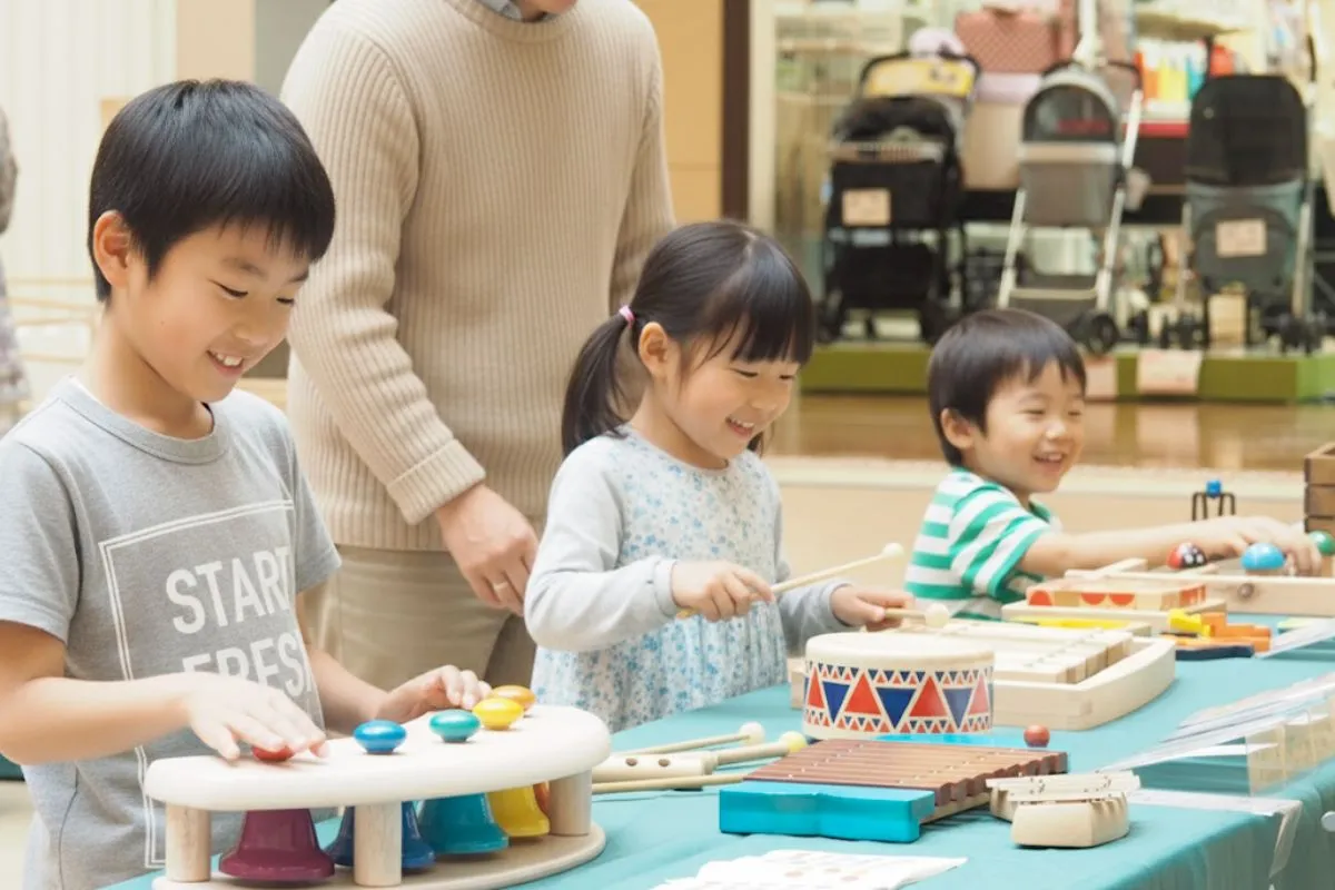 ショッピングモール内で移動木育広場『木はいいなぁ』が開催され、多くの子どもたちが木製のアスレチック遊具や積み木で楽しそうに遊んでいます。家族連れで賑わうイベントの様子。